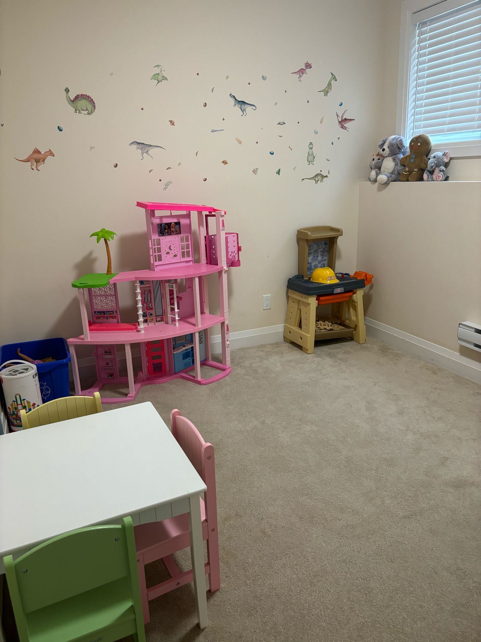 Imaginative play room with dollhouse, workbench, and dinosaur wall